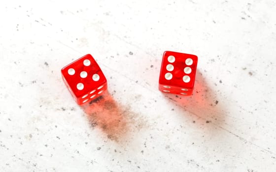 Two red craps dices showing Yo (Yo-leven) (number 5 and 6) overhead shot on white board
