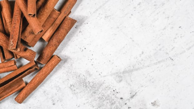 Closeup detail - Heap of cinnamon bark sticks on white stone board, empty space for text right side
