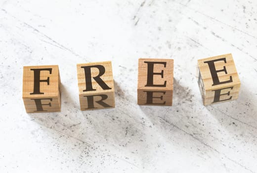 Four wooden cubes with word FREE on white working board.