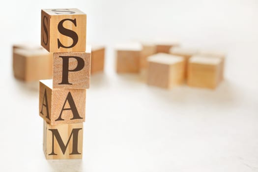 Four wooden cubes arranged in stack with word SPAM on them, space for text / image at down right corner
