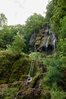 Waterfall Bad Urach at Southern Germany Longexposure. Cascade panorama in Bad Urach Germany is a popular natural attraction and waterfall sight called Uracher Wasserfall . Natural reserve in autumn season with colorful foliage and longtime exposure. Panoramic view of Bruehlbach creek or brook with cascade in Bad Urach, Germany near waterfall sight Uracher Wasserfall . Natural reserve on a summer morning after heavy rain in lush forest.