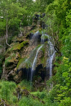 Waterfall Bad Urach at Southern Germany Longexposure. Cascade panorama in Bad Urach Germany is a popular natural attraction and waterfall sight called Uracher Wasserfall . Natural reserve in autumn season with colorful foliage and longtime exposure. Panoramic view of Bruehlbach creek or brook with cascade in Bad Urach, Germany near waterfall sight Uracher Wasserfall . Natural reserve on a summer morning after heavy rain in lush forest.