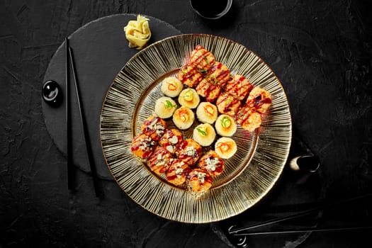 Exquisite baked sushi rolls topped with golden brown cheese hats designed for two served on luxurious gold textured plate with two pairs of chopsticks and soy sauce on dark stone table