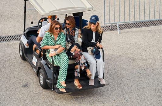 Monaco, Monte Carlo, 29 September 2022 - several beautiful women are riding in an electric car at the famous motorboat exhibition, mega yacht show, clients and yacht brokers discuss the novelties. High quality photo