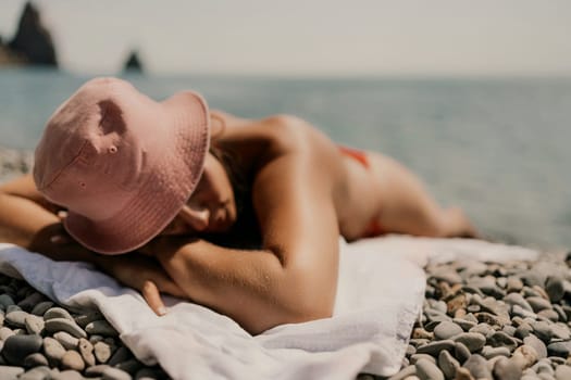 A woman sunbathes on the beach, lying on her stomach in a red swimsuit against the sea backdrop