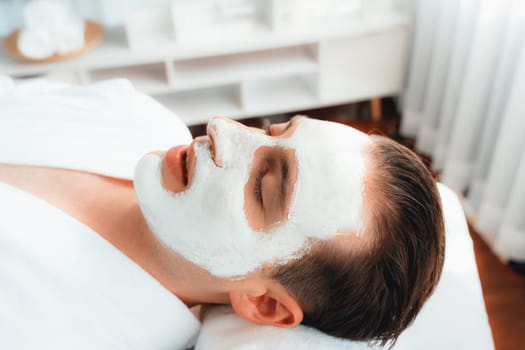 Serene ambiance of spa salon, man customer indulges in rejuvenating with luxurious face cream massage with modern daylight. Facial skin treatment and beauty care concept. Quiescent