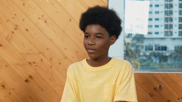 Smiling african boy sitting in circle while listening diverse friend sharing idea in group therapy with trust. Highschool student thinking and learning about mental health problem. Edification.