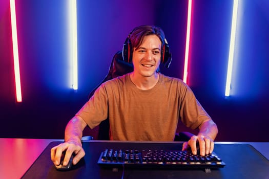 Host channel of gaming smart streamer playing online game to be winner, wearing headphone with viewers live steaming on media social online for selected team competition at neon light room. Pecuniary.