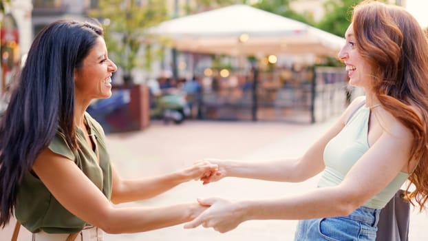 Redheaded woman and brunette woman embrace in the street in an emotionally charged encounter