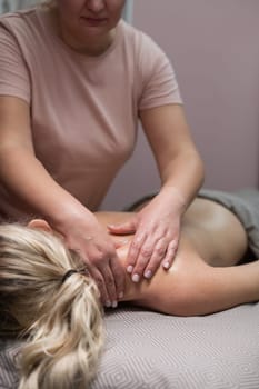 A woman undergoing a massage of the cervical-collar area. Vertical photo