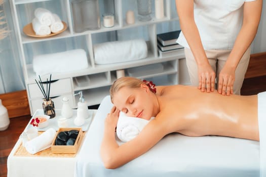 Caucasian woman customer enjoying relaxing anti-stress spa massage and pampering with beauty skin recreation leisure in day light ambient salon spa at luxury resort or hotel. Quiescent