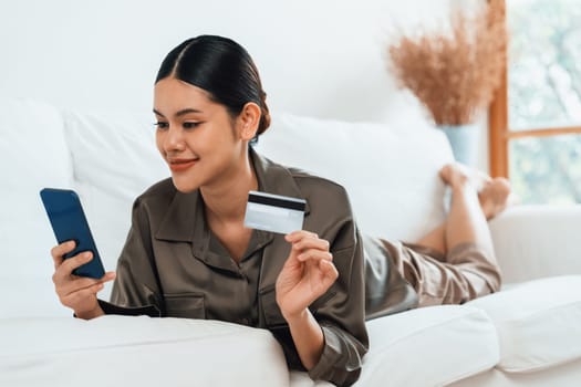 Young happy Asian woman buy product by online shopping at home while ordering items from the internet with credit card online payment protected by uttermost cyber security from online store platform