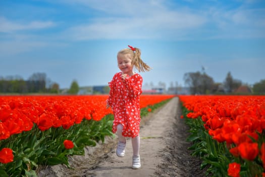 Happy girl running in a red tulip field