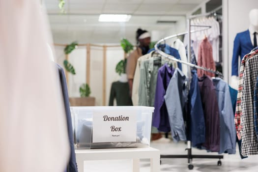 Donation box filled with used clothing for charity in shopping mall boutique. Container with second hand apparel for humanitarian aid in fashion garment shop with no people inside