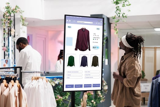 Young client search for clothes on board in clothing store boutique, self ordering interactive monitor. Trendy shopper buying modern fashion items on kiosk service display, retail store concept.