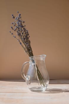 Lavender flowers in glass dishes. Dried herbal flowers on beige background. Minimal still life eco concept. Ideal space for displaying cosmetics with lavender extract. Copy space