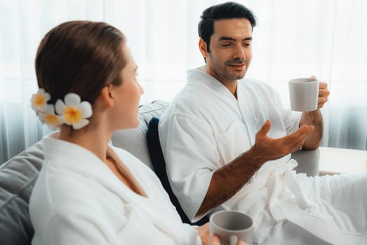 Beauty or body treatment spa salon vacation lifestyle concept with couple wearing bathrobe relaxing with drinks in luxurious hotel spa or resort room. Vacation and leisure relaxation. Quiescent