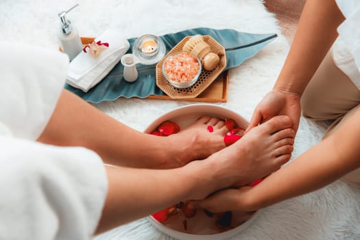 Man indulges in blissful foot massage at luxurious spa salon while masseur give reflexology therapy in gentle day light ambiance resort or hotel foot spa. Quiescent