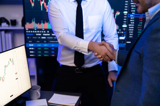 Investor stock trading of business partners shaking hands against screen for cooperating of investing agreement of highest valued technology product trending on the dynamic market stock. Sellable.