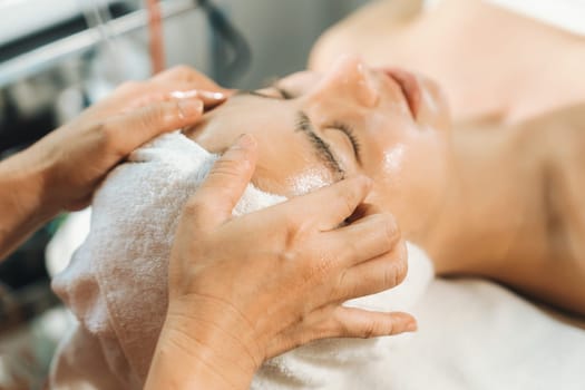 Beautiful caucasian woman lying on spa bed during having facial massage by professional hands at modern spa salon surrounded by beauty electrical equipment or medical equipment. Close up. Tranquility