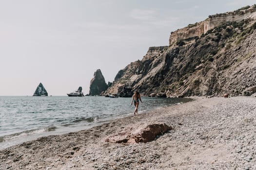 Woman beach vacation photo. A happy tourist in a blue bikini enjoying the scenic view of the sea and volcanic mountains while taking pictures to capture the memories of her travel adventure