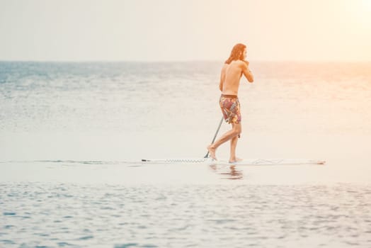 Asian man swimming in sea water and paddleboarding passing beautiful sea at summer sunset. Healthy strong male enjoy outdoor active lifestyle and water sports on holiday vacation