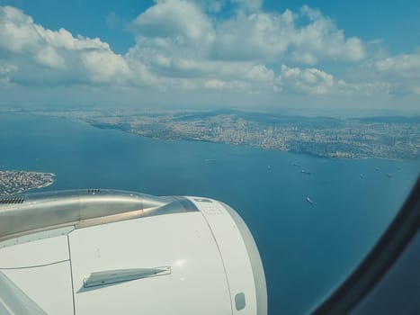 view from the airplane window and blue sky with white clouds, city Istanbul, sea and ships. soft focus.