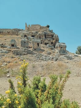 vertical photo of the ruins of the ancient city of Tlos, the acropolis against the blue sky. soft focus. Turkey