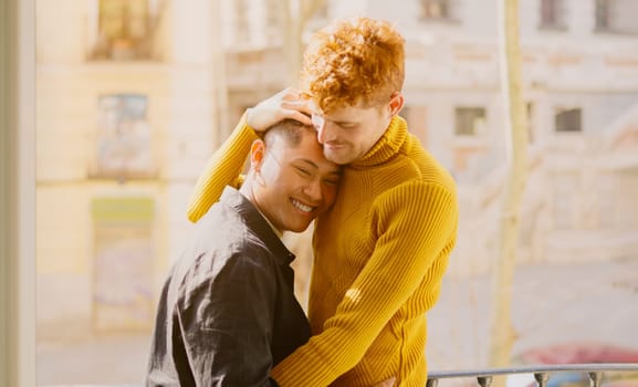 Multiethnic gay couple standing and embracing on the balcony at home