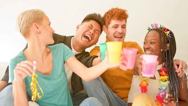 Multiethnic group of friends toasting and laughing while celebrate at home