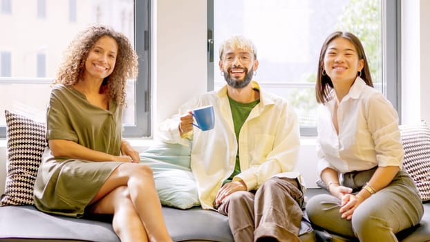 Coworkers smiling relaxed during coffee break sitting on comfortable chairs
