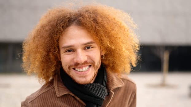 Alternative young man with curly hair smiling at camera