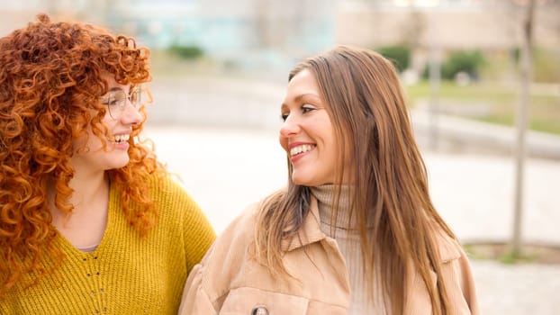 close up of female friends talking happily along the street