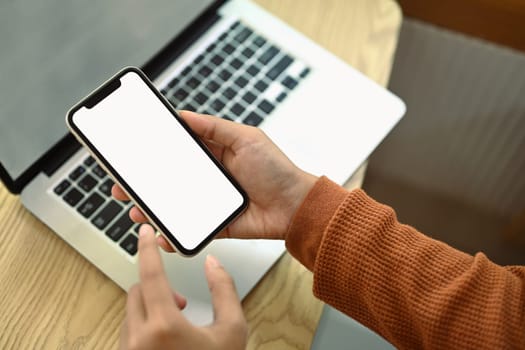 Woman hands using mobile phone at working desk. Empty screen for advertising and creative design.