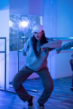 Young Asian woman practicing modern dance styles in a studio with neon light.