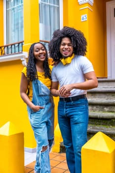 Vertical portrait of a cute african couple next to a yellow house