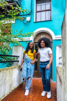 Vertical photo with copy space of a young casual african couple leaving a blue colorful house