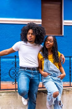 Vertical portrait of a distracted cool african couple embracing from the shoulder leaning on a railing