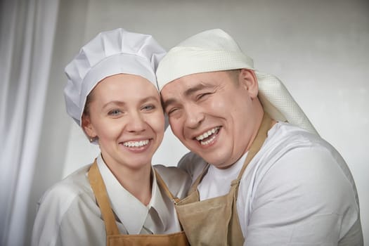 Cute oriental family with wife and husband cooking in kitchen on Ramadan, Kurban-Bairam, Eid al-Adha. Funny couple of cooks at joke photo shoot. Pancakes, pastries, Maslenitsa, Easter