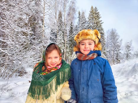 Two cute happy little cheerful children in winter snow forest. Photo shoot in stylized clothes of the USSR. Fur Hat with earflaps