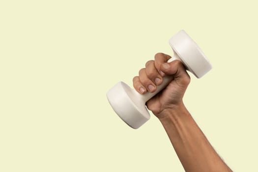 Black male hand holding a white dumbell isolated, light green background. High quality photo