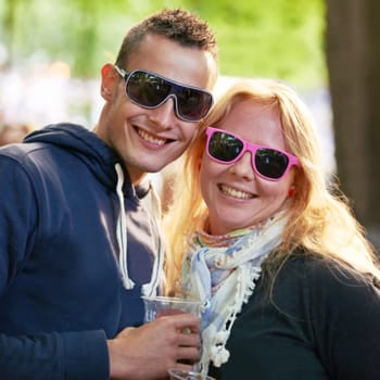 Portrait, hug and couple with sunglasses, music festival and romance with sunshine and weekend break. Face, people and embrace with woman and man with summer and bonding together with funky eyewear.
