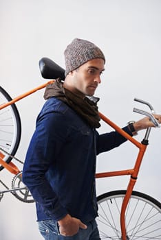 Bicycle, walking and man in building carrying bike for healthy and eco friendly transportation for travel. White background, thinking and cyclist with hipster and journey for carbon neutral commute.