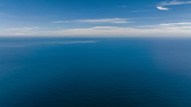 Aerial drone of open blue sea with waves against the sky and clouds. Seascape in the tropics. Borneo, Malaysia.