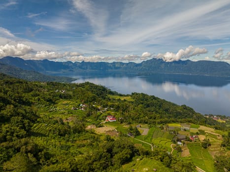 Aerial view of beautiful blue Maninjau lake and farmland in a volcano crater. Sumatra, Indonesia.