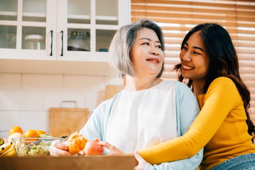 A portrait of an old mother and her adult daughter in the kitchen, holding an apple. Their smiles reflect the happiness and togetherness of family learning and teaching.