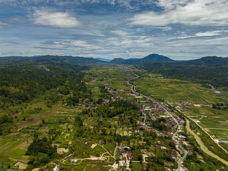 Aerial view of town in the valley among farmland and plantations with vegetables. Sumatra, Indonesia.