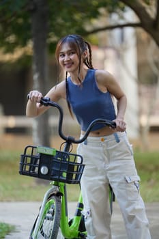 Happy Asian young woman ride bicycle in park, street city her smiling using bike of transportation, ECO friendly,, People eco lifestyle concept.