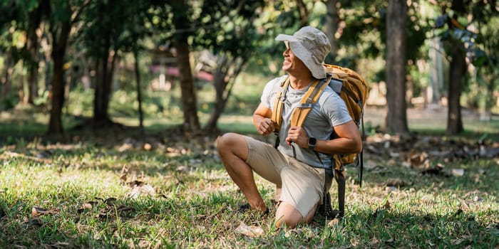 Young man backpacker traveling alone in forest. Attractive male traveler walking in nature wood during holiday vacation trip.