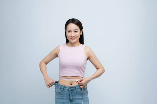 woman in old big jeans measuring her waist with tape, showing results of slimming diet